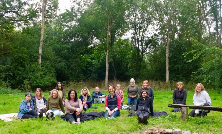 14 people sit in a clearing in the woods