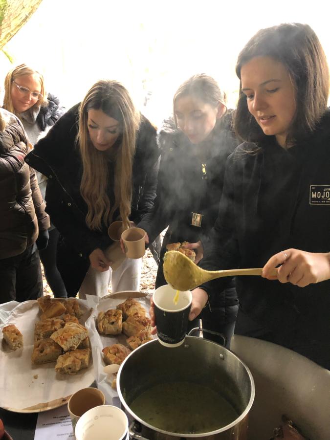 People serving themselves lunch in the woods